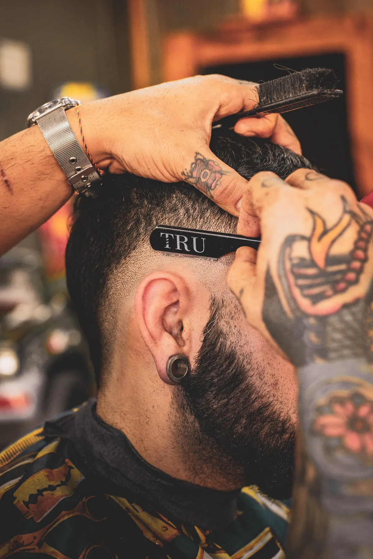 Barbier réalisant un dégradé au rasoir avec des lignes nettes
